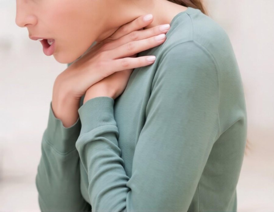 A person clutching their own throat with both hands, the universal sign of choking.