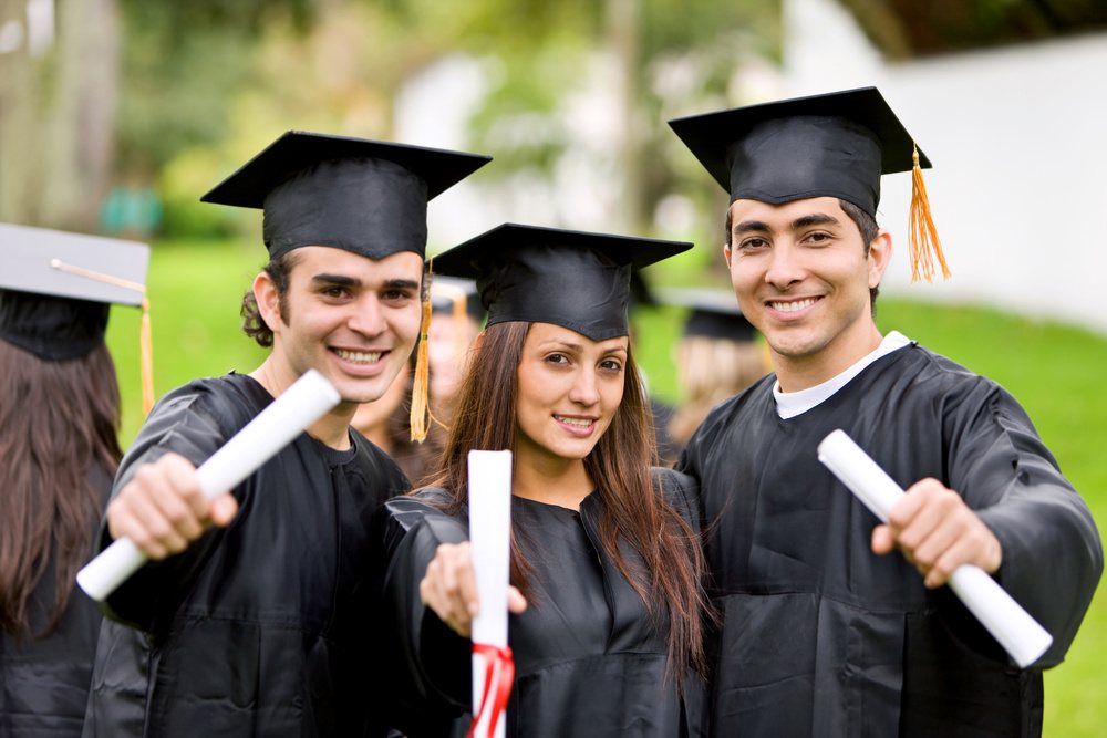 Graduates celebrating together holding diplomas.