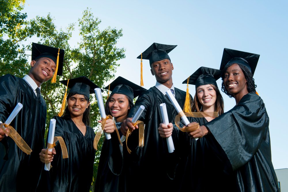 A group of graduates standing together with their diplomas.
